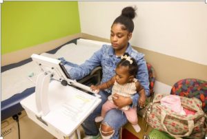 Titanna Brown holds her daughter, 9-month-old Nova Brown, during a childhood development screening at the Batson Kids Clinic in Jackson, Miss., Tuesday, April 18, 2023. Credit: Eric Shelton/Mississippi Today