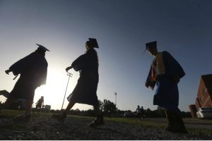 FILE - In this June 27, 2020, file photo, Saltillo High School seniors make their way to the football field as the sun begins to set for their graduation ceremony in Saltillo, Miss. The number of high school seniors applying for U.S. federal college aid plunged in the weeks following the sudden closure of school buildings this spring — a time when students were cut off from school counselors, and families hit with financial setbacks were reconsidering plans for higher education. (Thomas Wells/The Northeast Mississippi Daily Journal via AP, File)