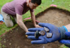 Chance Carden, project manager of Research and Curriculum at Mississippi State University, excavates a sectioned off area of what is thought to be a kitchen area, while Shawn Lambert, assistant professor of anthropology at MSU, shows shards of glass bottles found at the Prospect Hill Plantation in Lorman, Tuesday, June 20, 2023. Lambert said the rainbow-like patina on the glass shards is the soil eating away at the glass like a fungus.