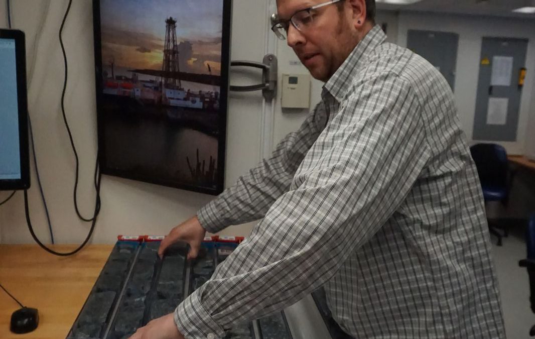 Dr. Jeremy Deans prepares halved cores of serpentinized peridotite for analysis in the core lab of the scientific drilling ship JOIDES Resolution. Photo credit: Lesley Anderson