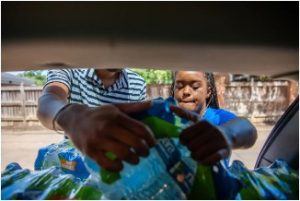 Maisie Brown, right, delivers water to a Jackson resident on Sept. 1, 2022. Credit: Rory Doyle/Deep Indigo Collective for Mississippi Today