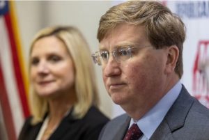 Gov. Tate Reeves, right, stands with his wife, Elee Reeves, as he answers questions from the media after signing qualifying paperwork to run for reelection at the Mississippi Republican Headquarters in Jackson, Miss., Tuesday, Jan. 3, 2023. Credit: Eric Shelton/Mississippi Today