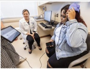 Dr. Olga Selioutski watches as Jessica Vann uploads information from her RNS device to a tablet.