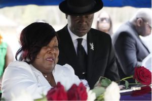 Bettersten Wade, mother of Dexter Wade, a 37-year-old man who died after being hit by a Jackson, Miss., police SUV driven by an off-duty officer, cries as she leaves a rose on her son's coffin in Jackson, Monday, Nov. 20, 2023. Attending to Wade is civil rights attorney Ben Crump, right. Wade was initially buried in a paupers cemetery without notifying his family after he was killed, and was recently exhumed. (AP Photo/Rogelio V. Solis)