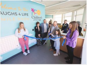 Kent Oliver and his daughter, Charlotte, 8, cut the ribbon for the Laughs 4 Life smile room at Children's of Mississippi.