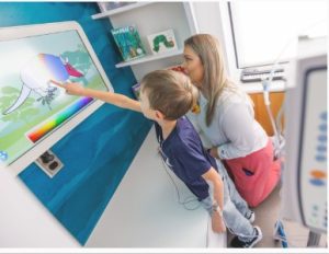 Children's of Mississippi patient Samuel Farve of Sumrall adds color to a creature while child life specialist Allyson Holliman looks on.