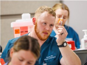 Second-year dental student Dutton Day prepares to learn how to administer a vaccine.