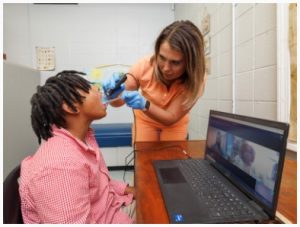 School nurse Christin Streif uses a scope to allow a physician to view Warren Central student Jaxson Wilson's throat during a telehealth visit.