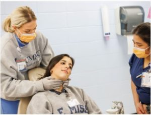 Nursing student, Junnah Mondejar, watches as dental hygiene students, Anna Shaw, left, and Mary Gillespie, demonstrate how to conduct an oral cancer screening.