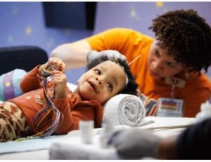 True Burns of Jackson smiles as neurophysiology tech Jazmine Anderson prepares her for an EEG at the Comprehensive Epilepsy Center at Children's of Mississippi.
