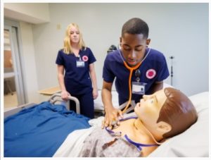 Nursing student Earlie Garth practices taking vital signs in the UMMC School of Nursing's simulation center at the South Oxford Center. Looking on is classmate Allie White.