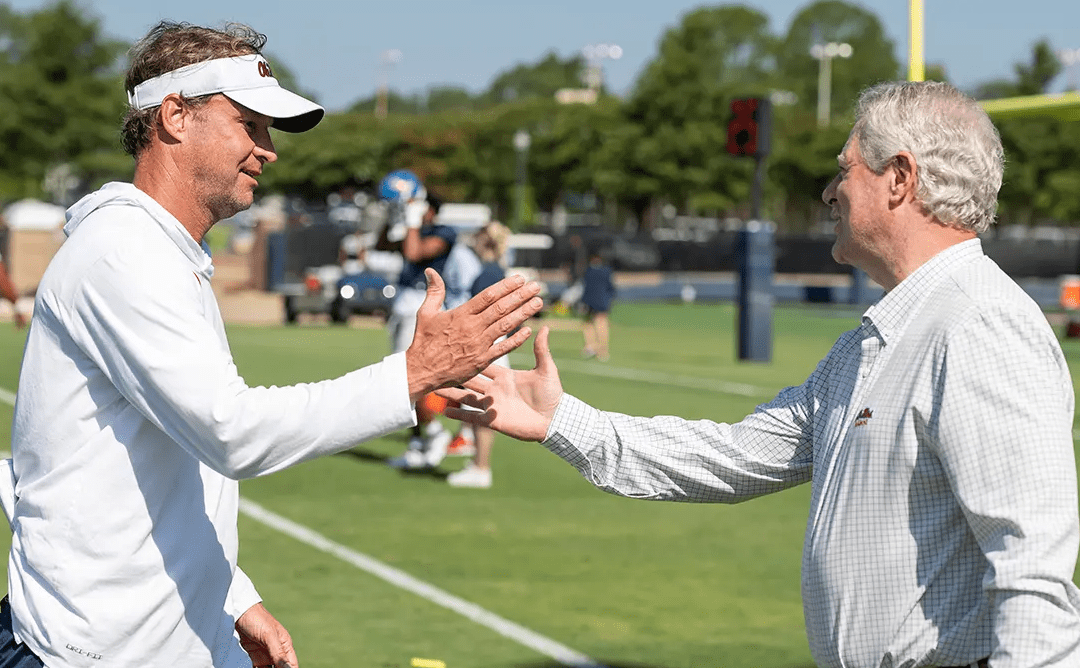 hancellor Glenn Boyce (right) greets coach Lane Kiffin at an Ole Miss football practice. Boyce has been named to a two-year term on the NCAA Board of Governors and a four year-term on the board of directors. (Photo by Thomas Graning/Ole Miss Digital Imaging Services)