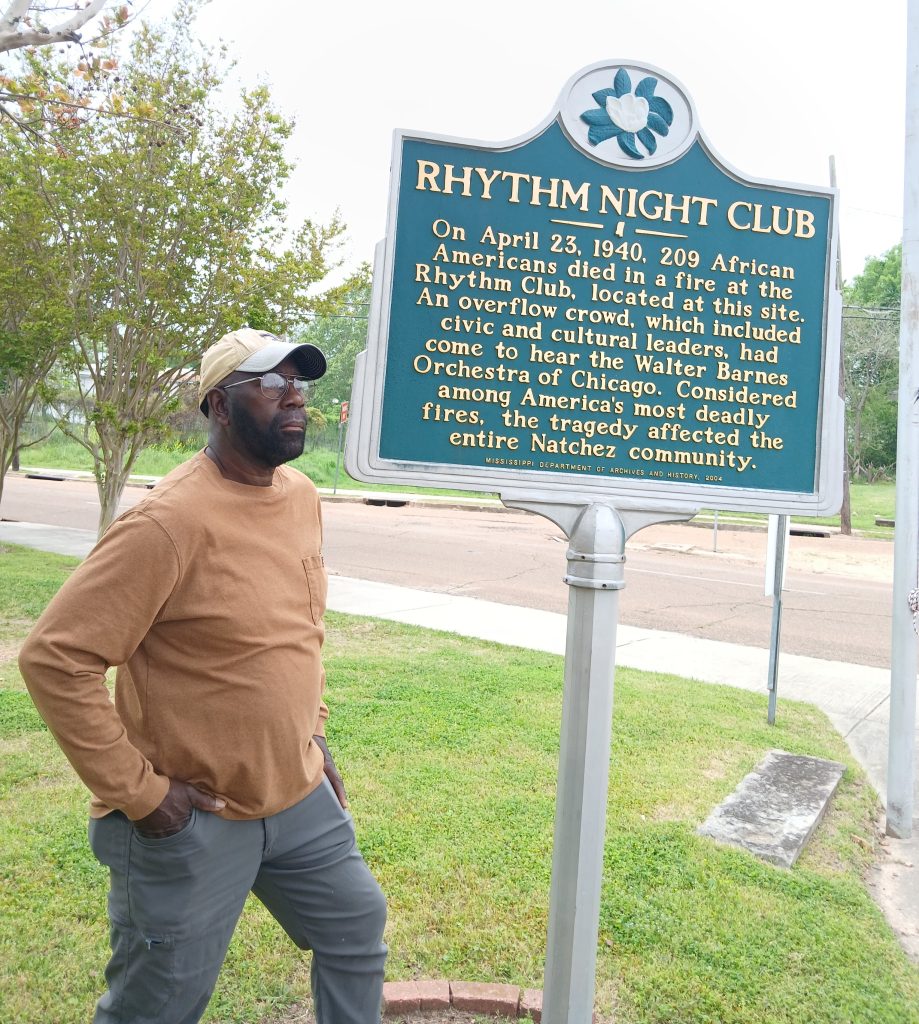 Monroe Sago, co-owner of the Rhythm Night Club Memorial Museum, is pictured with the historical marker that tells the story of the Rhythm Night Club Fire.