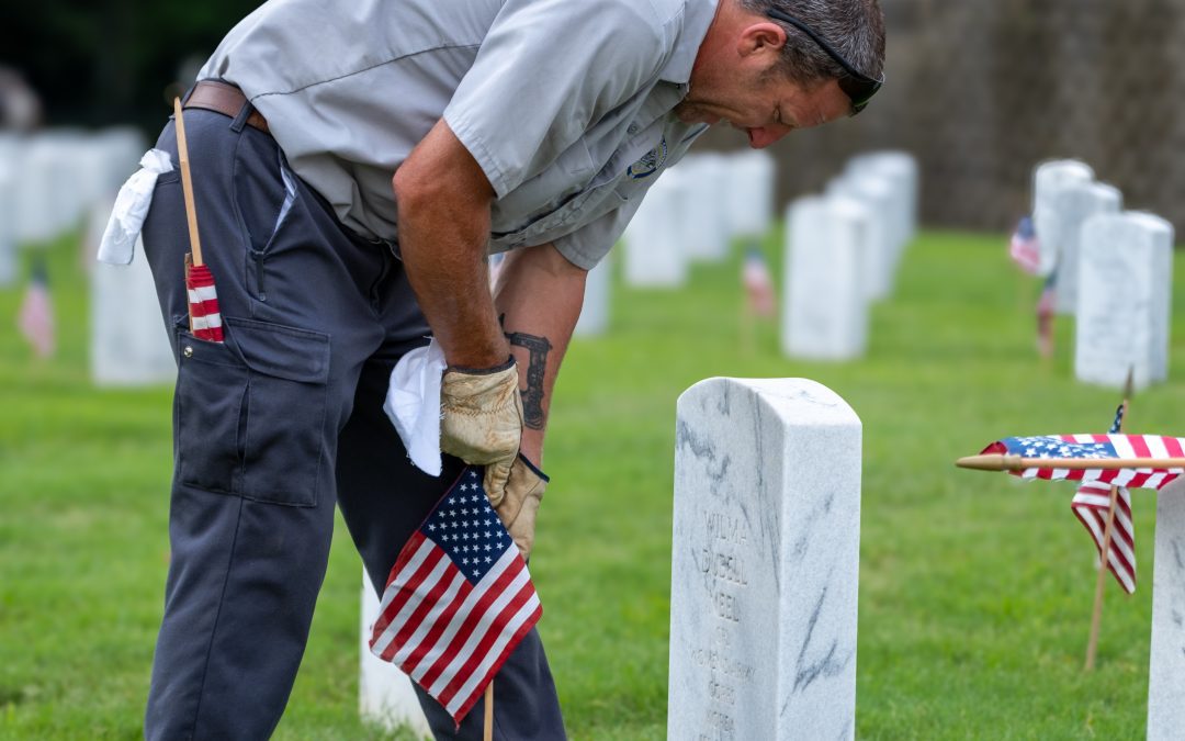 Anthony Cupit, cemetery caretaker at Natchez National Cemetery, places a flag on the gravesite of a U.S. military veteran in 2024. Photo courtesy of Caleb Q. Ray of the Natchez National Cemetery