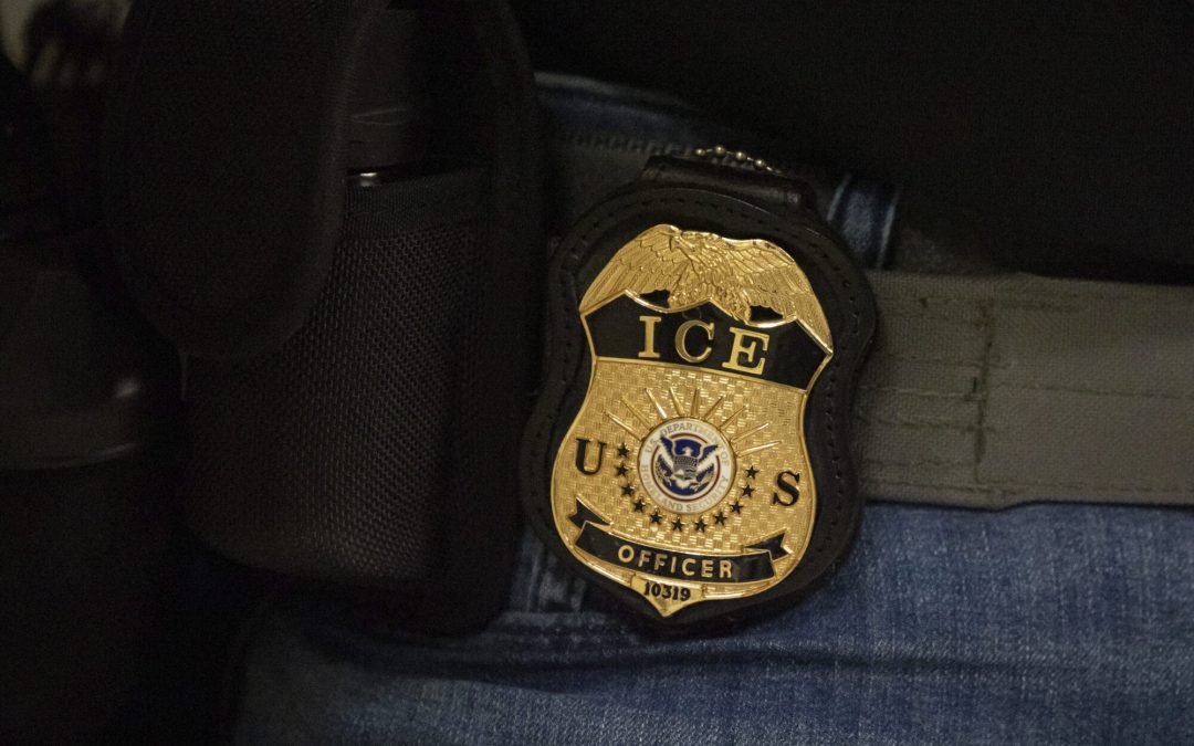 A federal agent wears a badge of Immigration and Customs Enforcement while standing outside an immigration courtroom at the Jacob K. Javits Federal Building in New York, Tuesday, June 10, 2025. (AP Photo/Yuki Iwamura)