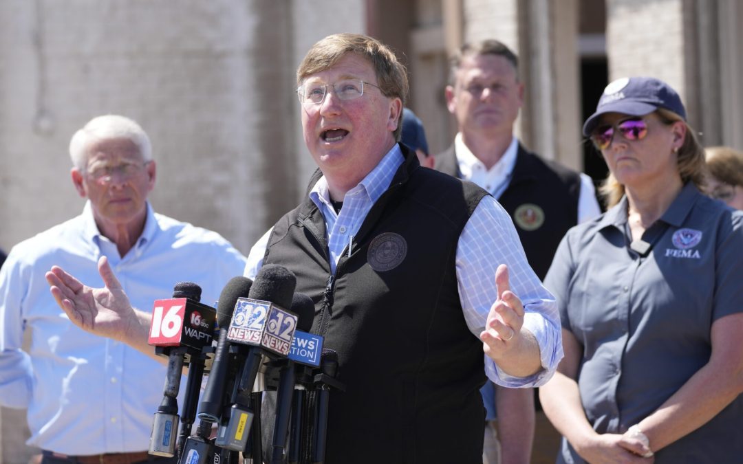Mississippi Gov. Tate Reeves speaks to reporters, Sunday, March 26, 2023 in Rolling Fork, Miss., about the Friday night tornado that hit Rolling Folk, Miss., and other areas. Deanne Criswell, right, Administrator for the Federal Emergency Management Agency, and U.S. Sen. Roger Wicker, R-Miss., left, were among the federal officials that joined local officials in touring one of the neighborhoods hit by the tornado. (AP Photo/Rogelio V. Solis)