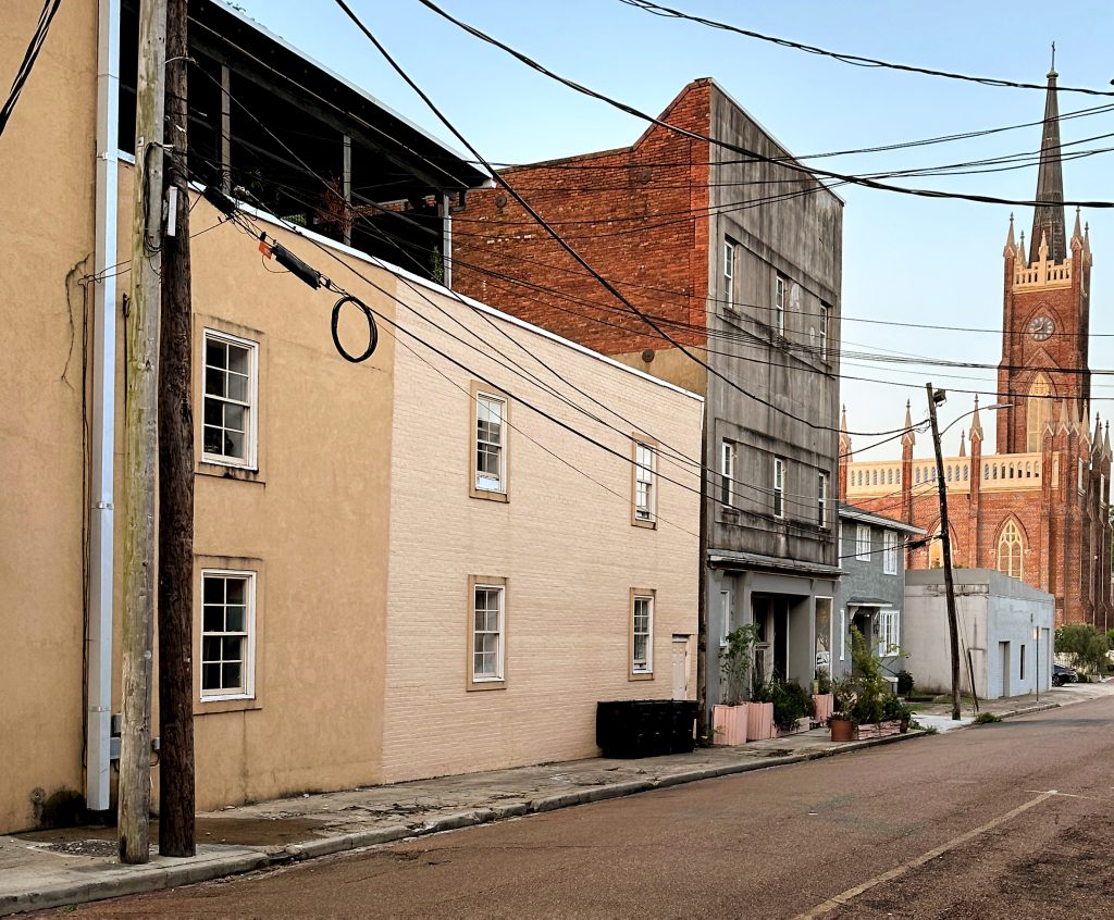 The original site of the building that housed the Bluff City Savings Bank was located to the left (or north) of the building with the pink flower pots in front. This three-story building was once a Natchez fire station. Photo by Ben Hillyer.