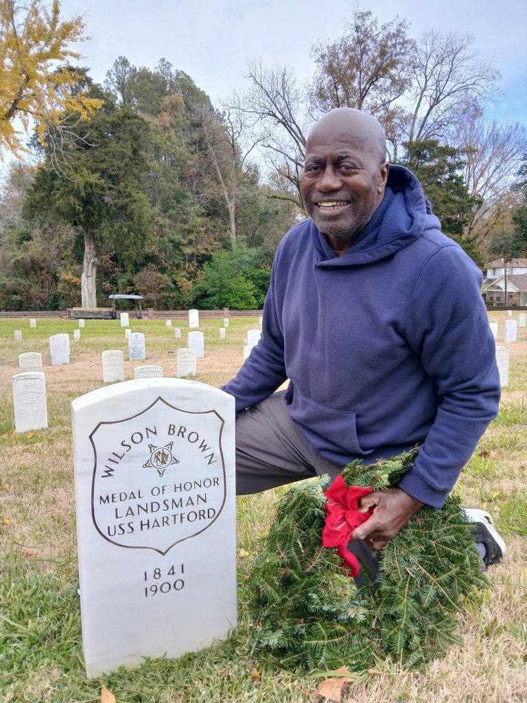 Ben Tucker, a volunteer with Home with Heroes, placed a wreath on the grave of Landsman Wilson Brown, a Medal of Honor recipient, during his 2024 participation in the Wreaths Across America program.