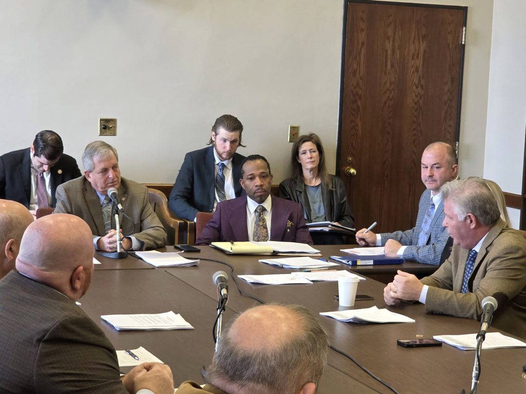 At left, Rep. Donnie Scoggin (R) speaks with Rep. Rob Roberson (R), at right, about the potential of consolidating the state's public universities during Wednesday's meeting of the House Universities and Colleges Committee. (Photo by Jeremy Pittari | Magnolia Tribune)