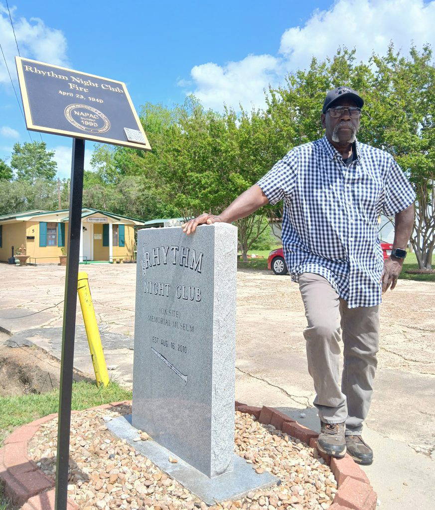 Monroe Sago, co-owner with his wife Betty of the Rhythm Night Club (On Site) Memorial Museum, stands at the historical marker in front of the museum. Photo by Roscoe Barnes III