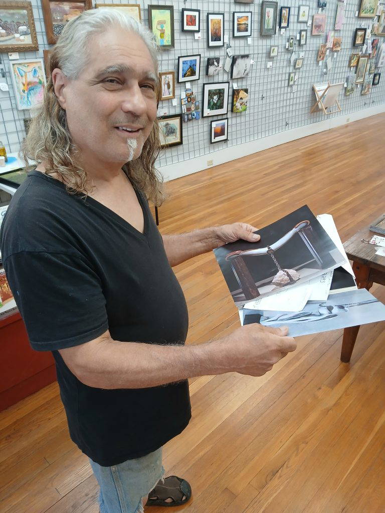 Armand Saiia, ArtsNatchez’s Artist of the Month for June, displays photographs of his sculptures at the gallery.Photo by Roscoe Barnes III