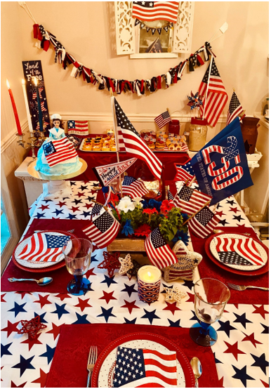 The Fourth of July tablescape of my dreams, Courtesy of red, white and blue linens and dishes;
festive centerpiece of flowers, flags and a red lantern
and holding court on the left, foreground, a
homemade Betsy Ross cake. (Photo by Kara Kimbrough)