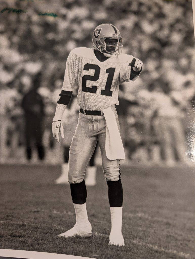 Garry Lewis (#21), cornerback for the Los Angeles Raiders, points to an offensive player while signaling to his teammates that he'll take him.Photo courtesy of Garry Lewis