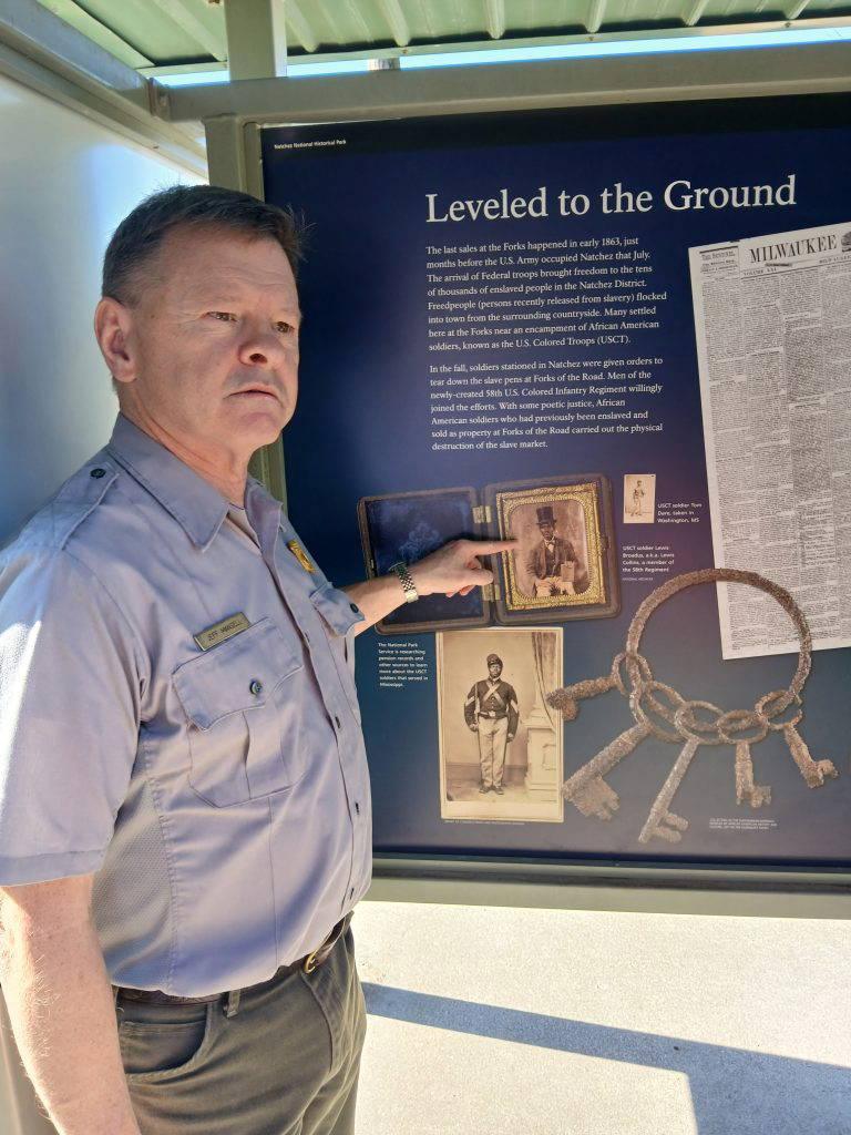 Lead Historian Jeff Mansell points to a historic photograph featured on a new interpretive panel in the free-standing kiosk at the Forks of the Road site.